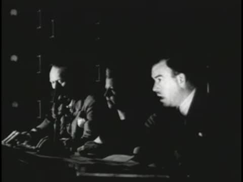 Audio engineers at a console in a dark television control room.