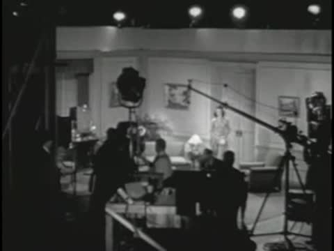 TV studio set with cameras and crew working behind scenes.