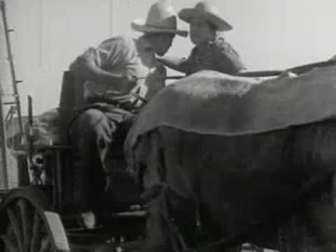 Two people sitting on a cart on a farm, historical archive footage