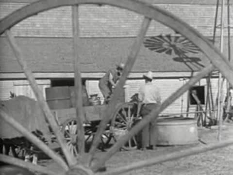 A windmill in the background as people work around a cart, prelinger film