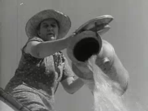 A person pouring liquid from a large container, agricultural documentary shot