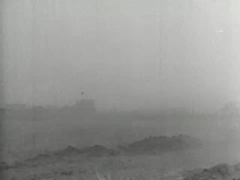 Wide shot of a small farmhouse shrouded in heavy blowing dust, 1930s