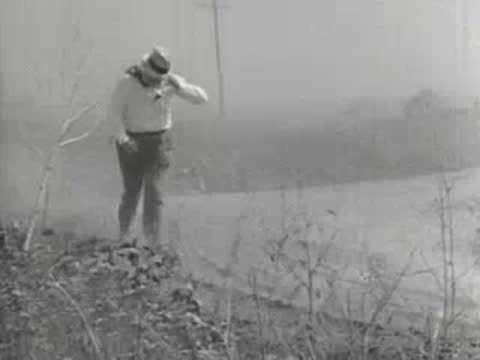 Medium shot of a person struggling to walk against heavy wind and dust, 1930s