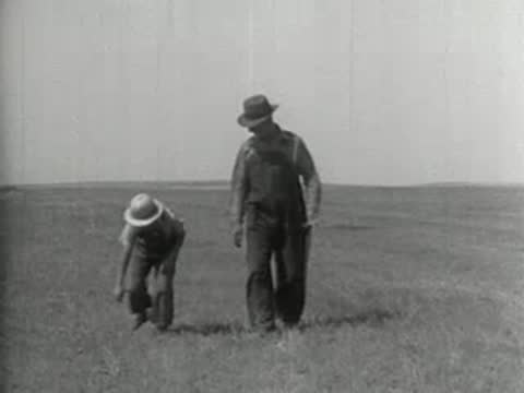 A farmer and a child in an empty field, rural America 1930s