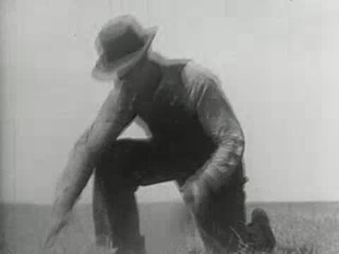 A farmer kneeling down and letting dry soil slip through his hands
