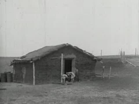 A small sod house with a thatched roof in a dry landscape