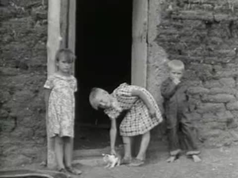 Children standing outside the entrance of a small sod house