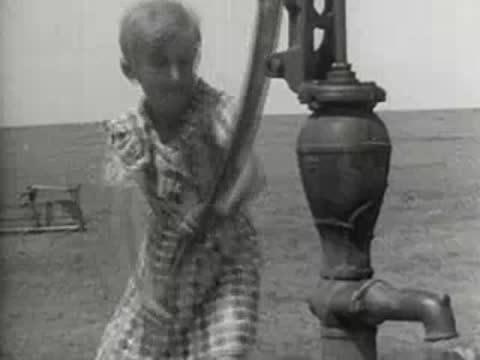 A child pumping water from a cast iron water pump outdoors
