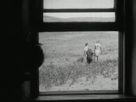View from inside a house looking out at figures walking in a field