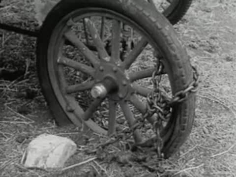 Close-up of an old wooden wagon wheel chained in the dirt