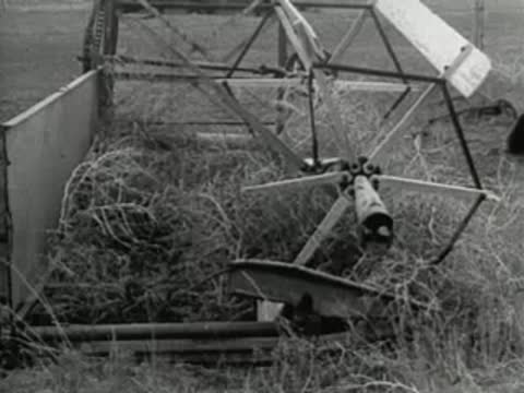 Agricultural machine harvesting crops in a field, old documentary footage.