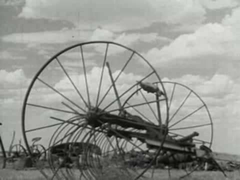 Large antique hay rake in a field under a cloudy sky.