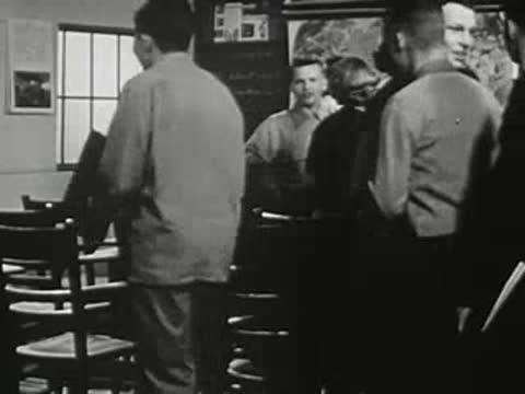 Students standing and talking in groups inside classroom.