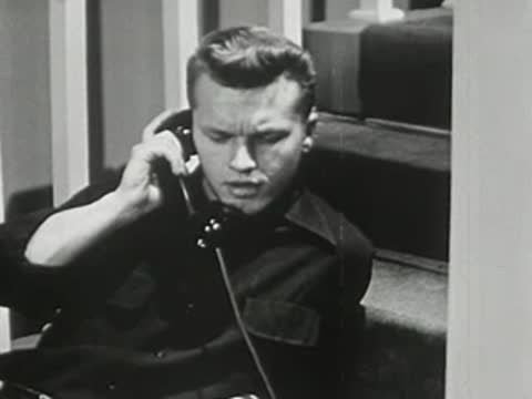 Teenager talking on telephone while sitting on floor near stairs.