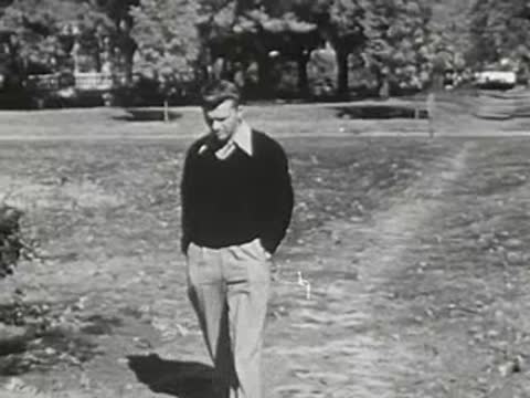 A young man walking towards the camera on a park path
