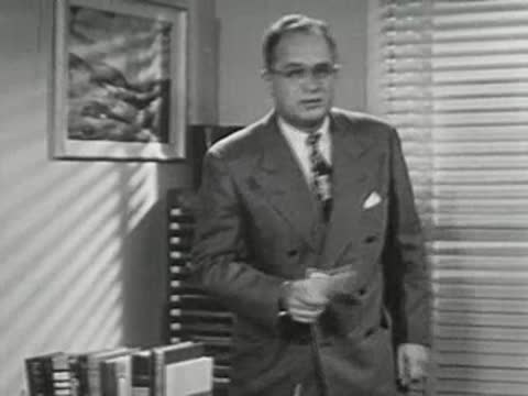 A man in a suit standing up from his office desk