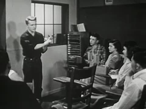 A young man giving a presentation in front of a classroom
