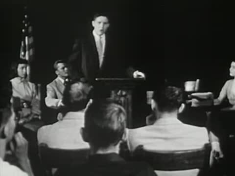 A speaker at a podium addressing an audience in a hall
