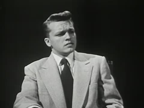 Close-up of a young man in a suit adjusting his tie