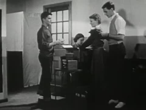 Students gathered around a desk in a school hallway
