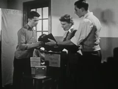 A group of students gathered around a desk in a hallway