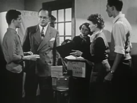 A group of students and an adult man in a classroom, discussing