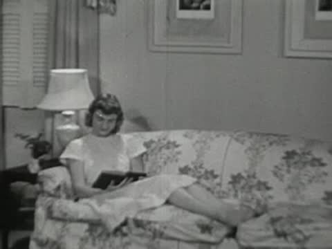 Girl reading a book comfortably seated on a sofa.