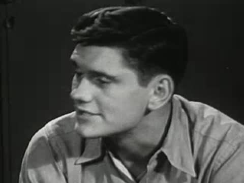 Medium shot of a young man talking, looking to the side.