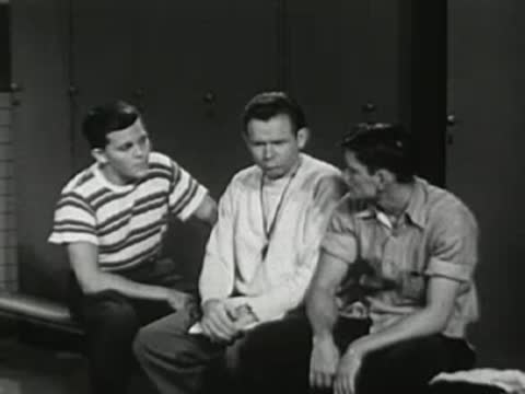 Three young men sitting side by side, conversing and listening.