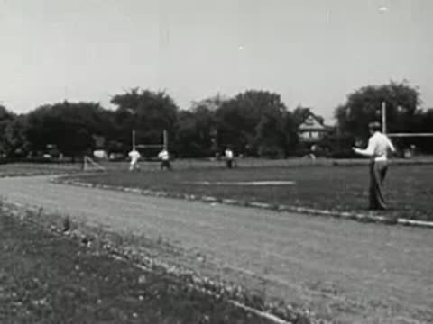 Track and field view showing runners practicing in the background.