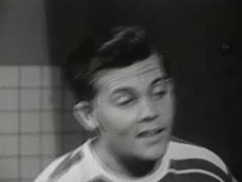 Close-up of a young man speaking animatedly, 1940s hairstyle.
