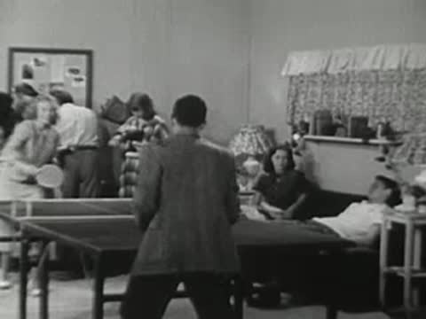 People gathering in a recreation room with a ping pong table.
