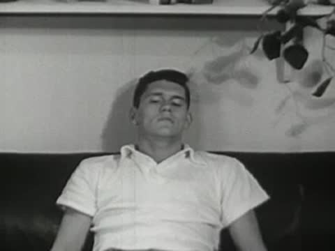 Young man lying asleep on a couch, resting indoors.