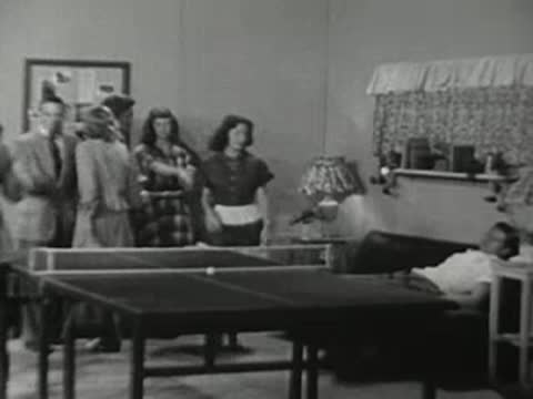 People socializing in a room with a ping pong table.