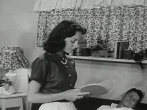 Woman holding a ping pong paddle near a sleeping man.