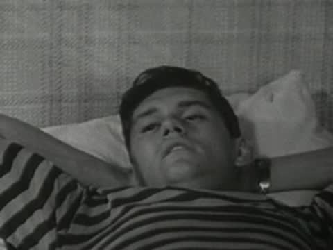 Boy waking up in bed, stretching arms behind head.