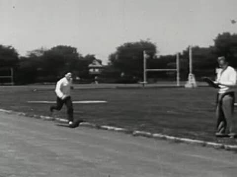 Coach watching a runner sprint past on the track.