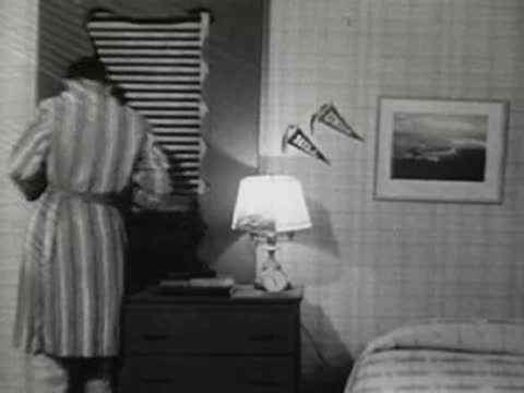 A teenager in a bathrobe turns off the lamp and prepares for bed.