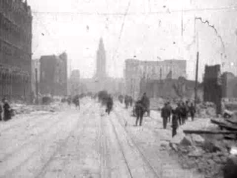 Pedestrians and debris along a wide street leading toward a distant tall tower.