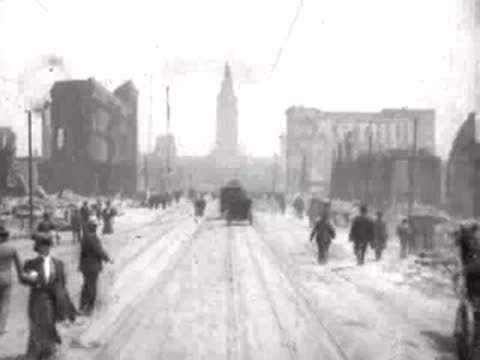 Pedestrians walking past a horse-drawn wagon on a debris-lined city street.