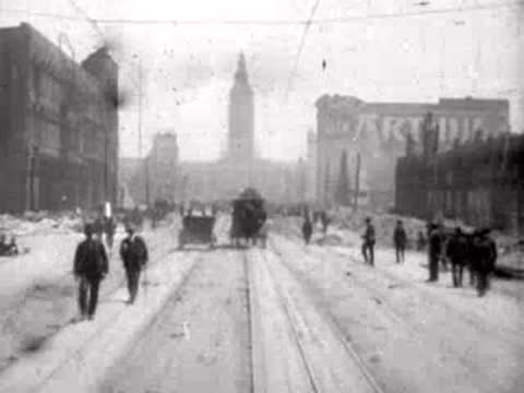 Pedestrians walking toward the camera on a debris-flanked city street.