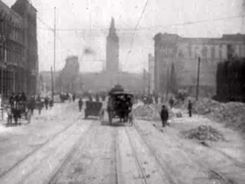 Horse-drawn carriage and pedestrians on a debris-strewn city street.