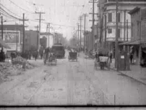 Urban street leading into the distance with distant vehicles and pedestrians.
