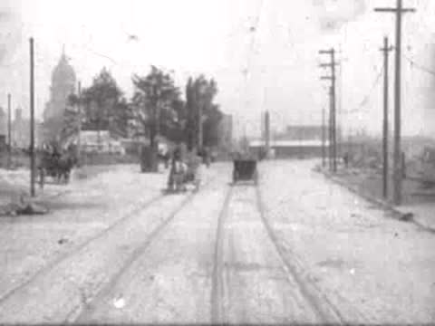 Road moving toward a distant city skyline framed by utility poles.