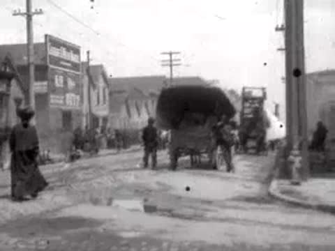 Crowded San Francisco street with horse-drawn carriages and pedestrians after the 1906 earthquake.