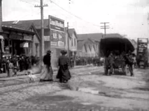 Crowded San Francisco street with horse-drawn carriages and pedestrians after the 1906 earthquake.