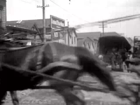 Horse-drawn carriage speeding past the camera on a crowded San Francisco street in 1906.