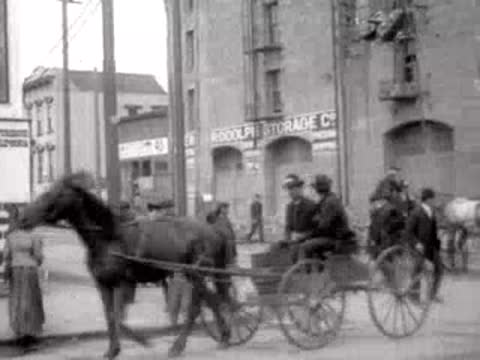 Horse-drawn carriage moving down a San Francisco street past brick buildings in 1906.