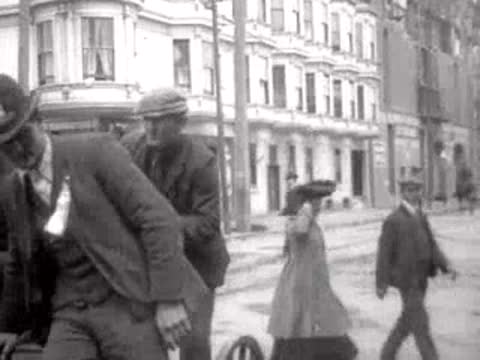 pedestrians walking past buildings on San Francisco street, historical footage