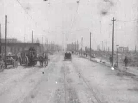damaged street with horse-drawn carts in distance, historical footage
